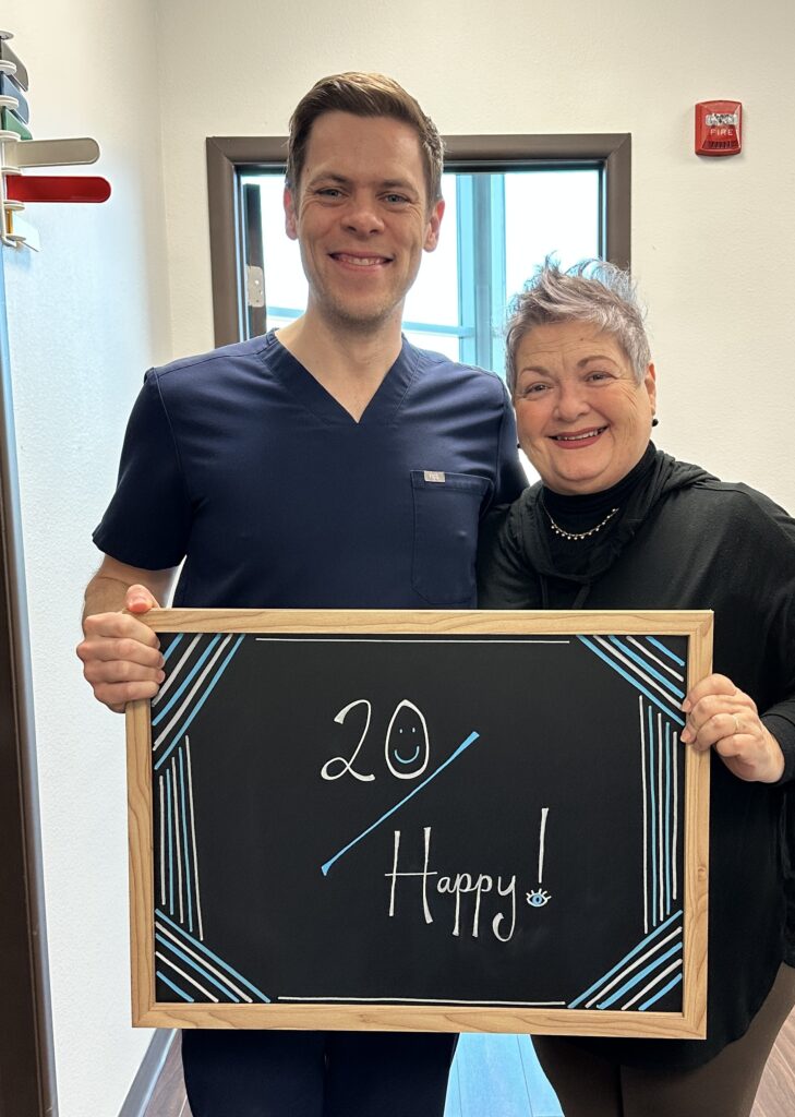 Dr. McNutt and patient smiling while holding a “20 Happy!” sign at Physicians Eye Clinic of Laredo.