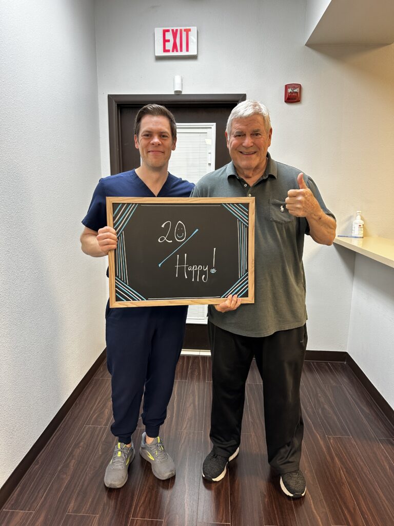 Dr. McNutt with a happy patient holding a “20 Happy!” sign at Physicians Eye Clinic of Laredo.